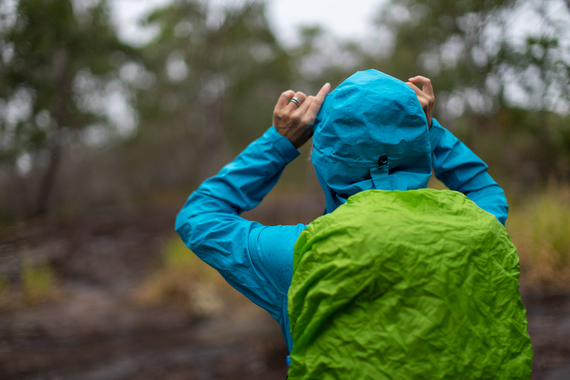 Hiker wears a rain jacket and has cover on her day pack. 