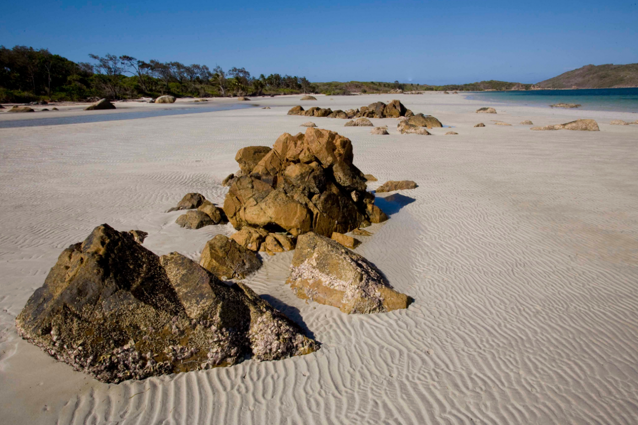 White sandy beach with large rocks scattered in the sand